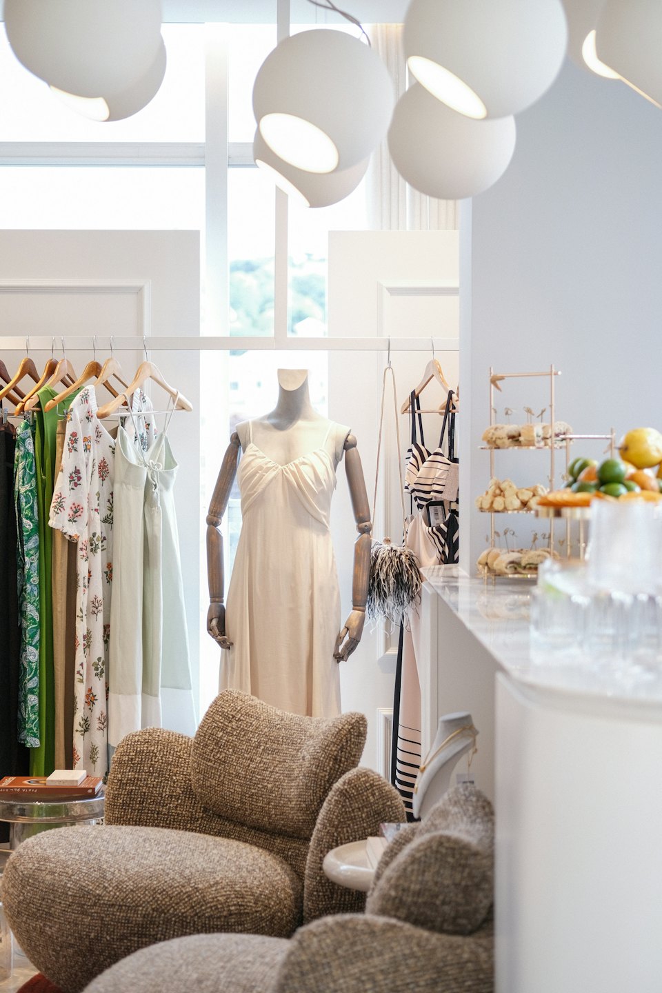Mannequin in cream dress inside a modern clothing boutique.